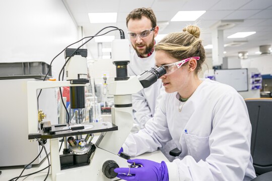A man and women scientist looking in a microscope