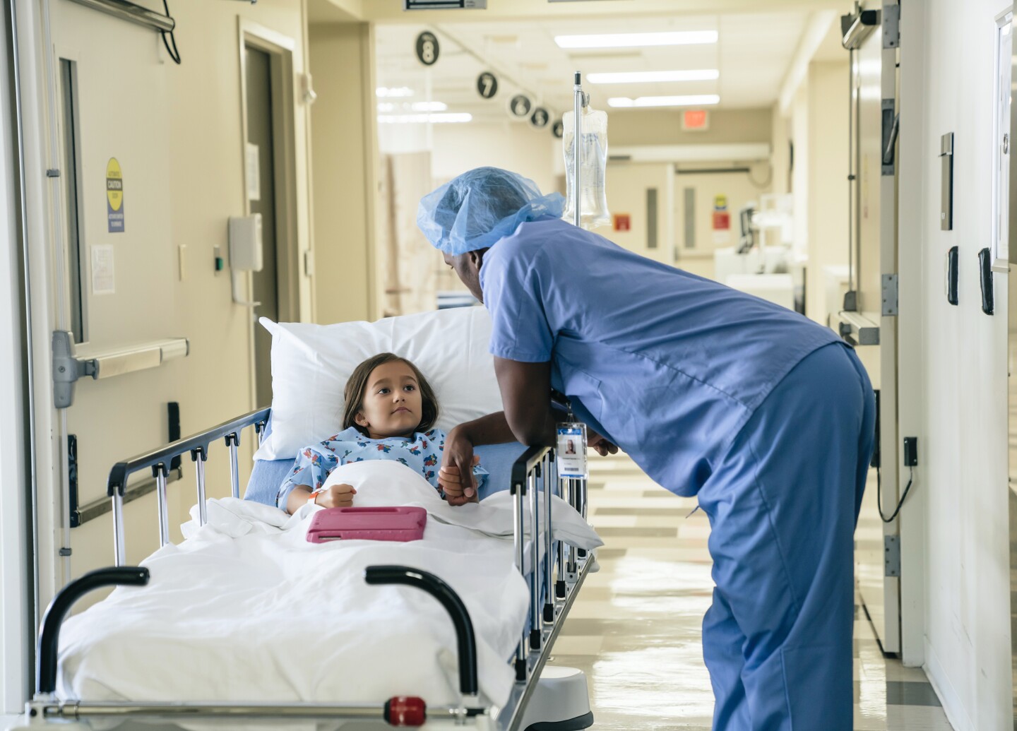 Doctor holding hand of girl in hospital gurney