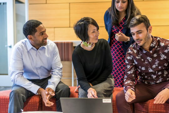 A diverse group of people sitting in front of a computer